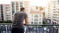 Man enjoying view from his hotel suite balcony on busy street, business trip Royalty Free Stock Photo