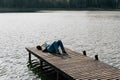 A man enjoys a sunny autumn day, resting lying on a wooden boat dock on a lake outside the city Royalty Free Stock Photo