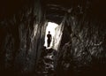 Man in the entrance of a deep narrow cave. Royalty Free Stock Photo