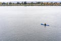 Man in equipment rides kayak on the Columbia River with number of houses on the shore