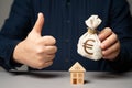 A man with a euro money bag approves a real estate deal. Buy or sell a house. Royalty Free Stock Photo