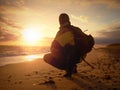 Man at evening sea. Hiker with backpack with hands in pocket along beach.