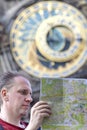 Man examines the map on background of historical medieval astronomical Clock on the Old Town Hall in Prague, Czech Republic Royalty Free Stock Photo