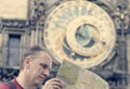 Man examines the map on background of historical medieval astronomical Clock on the Old Town Hall in Prague, Czech Republic, retro Royalty Free Stock Photo