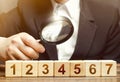 Man examines the numbered blocks with a magnifying glass. Study business plan instructions, contract roadmap. Organization