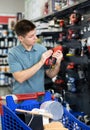 Man examines tool and buys electric drill, collects necessary supplies in store according to list for apartment repairs Royalty Free Stock Photo