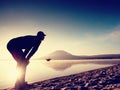 Man exercising on beach. Silhouette of active man exercising and stretching at lake Royalty Free Stock Photo