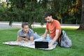 Man explaining something to friend in laptop. Happy students studying at park and smiling. Group of students talking outdoors, sha Royalty Free Stock Photo