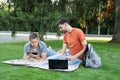 Man explaining something to her friend in laptop. students studying at park and smiling. Group of students leusure, talking outdoo Royalty Free Stock Photo
