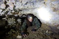 Man explores narrow cavern passage in abandoned underground limestone mine Royalty Free Stock Photo