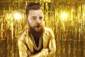 Man in extravagant golden jacket with gold chain around neck looking at camera with mistrust Royalty Free Stock Photo