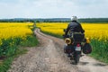 Man extreme sport riding touring enduro motorcycle on dirt. beautiful yellow field of flowers. World adventure rider. Tourist bike