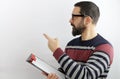 Man with eyeglasses wearing casual clothes with clipboard pointing to the side with his finger Royalty Free Stock Photo