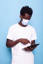 Man with face mask looking at screen of tablet in studio