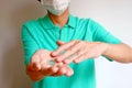 Man with Face Mask Using Alcohol Cleansing Gel Rubbing His Hands to Prevent the Infection Royalty Free Stock Photo
