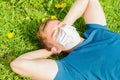 Man in face medical mask lies on green grass