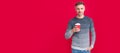 Man face portrait, banner with copy space. smiling grizzled guy in sweater drink coffee on red background, morning.