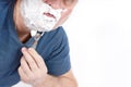 A man face in shaving foam shaves with a safety razor Royalty Free Stock Photo