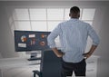 Man facing away looking out office window while data is on computer screen Royalty Free Stock Photo