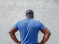 Rear view of man standing confidently with hands on waist, posing with arms akimbo and thinking Royalty Free Stock Photo