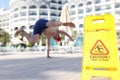 Man falling near yellow plastic sign caution wet floor closeup