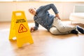 Man Falling On Wet Floor In Front Of Caution Sign Royalty Free Stock Photo