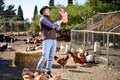 Countryman holding brown chicken in hands in hen house