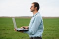 Man farmer working on a laptop in the field. Agronomist examines the green sprout winter wheat Royalty Free Stock Photo