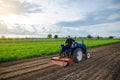 A man farmer works in a farm field. Cultivating the soil before planting a new crop. Milling, crushing and loosening ground. Royalty Free Stock Photo