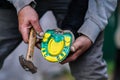 Man farrier installing plastic horseshoe to hoof. Closeup up detail to hands holding animal feet and hammer