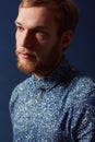 Man, fashion and serious face in studio with unique style, denim and trendy on blue background. Irish model with hipster