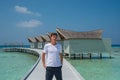 Man in fashionable white t-shirt and black shorts at over water villas at tropical island luxury resort Royalty Free Stock Photo