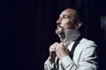 A man fastens buttons a white shirt in dark room