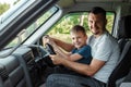 Man, father teaches little son to drive on the road. Parents and children, dad and son