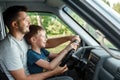 Man, father teaches little son to drive on the road. Parents and children, dad and son