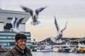 A man feeding a flock of seagulls in the Yokohama port. Birds in the city.