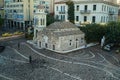 A man feeding pigeons at Monastiraki square in front of ancient Pantanassa church building in the morning with few tourists