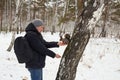 Man feeds squirrel while standing by tree in snowy forest during winter Royalty Free Stock Photo