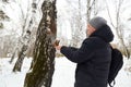 Man feeds squirrel while standing by tree in snowy forest during winter Royalty Free Stock Photo