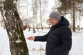 Man feeds squirrel while standing by tree in snowy forest during winter Royalty Free Stock Photo