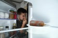 Man feeling bad smell of spoiled sausage in refrigerator, view from inside Royalty Free Stock Photo