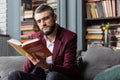 Man feeling thoughtful while reading book about astrology of money Royalty Free Stock Photo