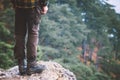 Man Feet on rocky cliff edge with forest aerial view