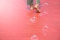 Man feet walking and white footprints on red wood floor in soft sunlight blurred background for concept of dirty marks and theft