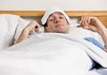 Man with fever laying in bed taking temperature