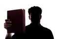 Man figure in silhouette showing a book