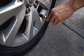 Man filling Air into the Tire. Car Driver Checking Air Pressure and Maintenance his Car by himself Royalty Free Stock Photo