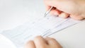 Man filling banking cheques for monthly payments and taxes