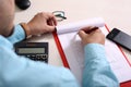 Man is filling form with pen. Picture of clipboard, glasses, mouse, calculator and phone on the table Royalty Free Stock Photo