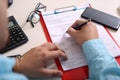 Man is filling form with pen. Portrait of clipboard, phone, glasses and calculator Royalty Free Stock Photo